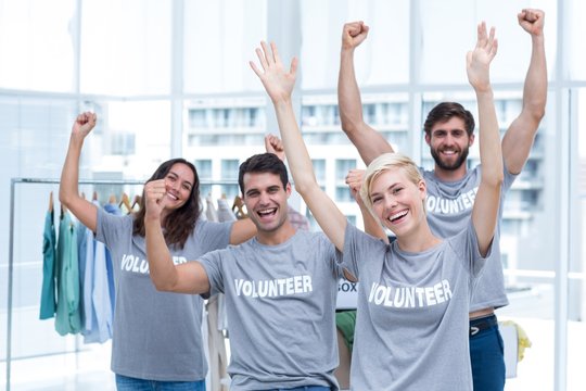 Happy volunteers friends raising arms