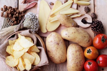 Potato chip and fresh potatoes on wood background
