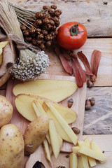 Potato chip and fresh potatoes on wood background