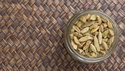 Cardamom spices in a mason jar over wicker background