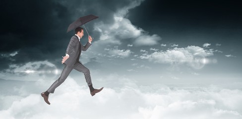 Fototapeta na wymiar Composite image of businessman jumping holding an umbrella