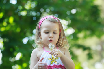 Blonde girl blowing on white Taraxacum officinale or common