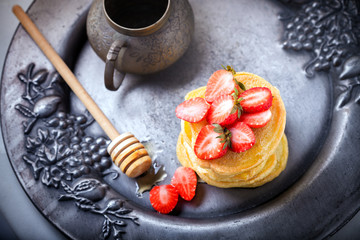 Stack of sweet pancakes with strawberry and honey.