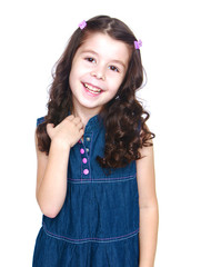 Fototapeta premium Cute little dark-haired girl in denim dress gently smiling, clos