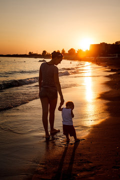 Siluhettes of mother and son by the sea at sunset