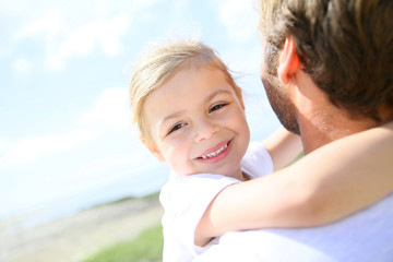 Portrait of cute little girl held in father's arms