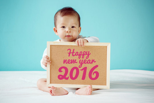 Baby writing "Happy New Year 2016" on the board, new family conc