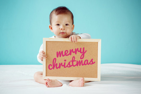 Baby writing "Merry Christmas" on the board, new family concept,