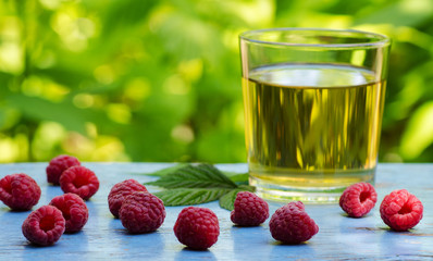 raspberries scattered on a table with a glass of tea