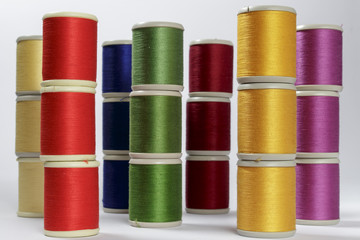 Several columns of bobbins of cotton thread for sewing machines with the colors of rainbow