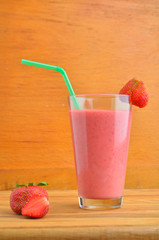 Milk shake with fresh berries and straw on wooden background