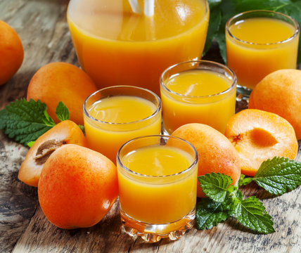 Fresh apricot juice and apricots with mint on old wooden table,