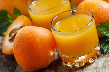 Fresh apricot juice and apricots with mint on old wooden table,