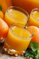 Fresh apricot juice and apricots with mint on old wooden table,
