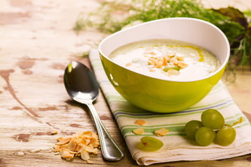 Cold green gaspacho soup with grapes, almonds and dill on grunge wooden rustic background....