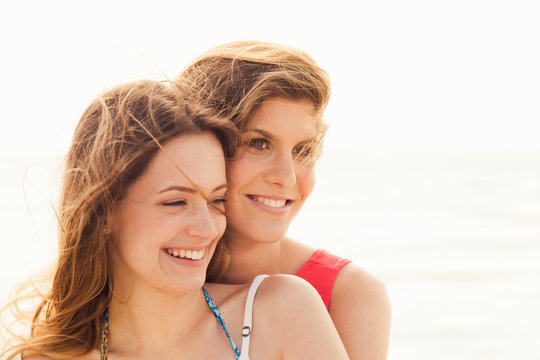 Beach in summer. A couple of young women in swimwear hugging affectionately in the sun on a summer day. Close-up photo of the smiling faces