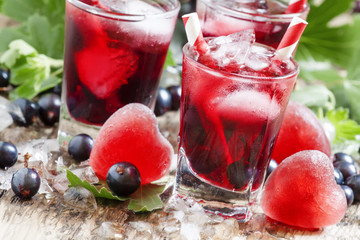 Red cold cocktail with berries currants and red heart-shaped ice
