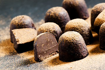 Homemade chocolate truffles with cocoa powder on dark background