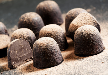 Homemade chocolate truffles with cocoa powder on dark background