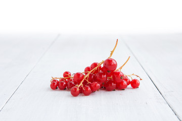 Fresh red currant on the light wooden background