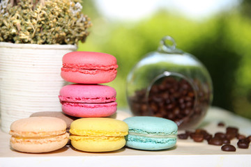 Colorful french macaroons with coffee on the nature background