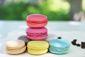 Colorful french macaroons with coffee on the nature background