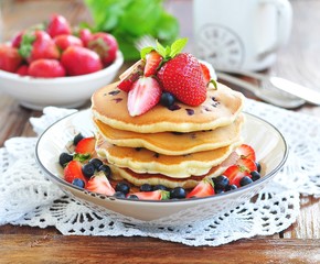 Blueberry Pancake with strawberries and a cup of milk on a wooden table