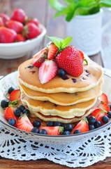 Blueberry Pancake with strawberries and a cup of milk on a wooden table