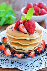 Blueberry Pancake with strawberries and a cup of milk on a wooden table