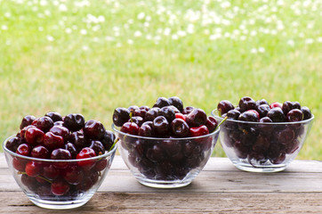 Cherries in 3 bowls on wood