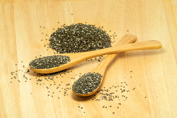 two wooden spoon of chia seed with blury pile of seed as backgro