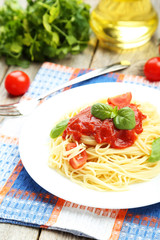 Spaghetti with tomatoes and basil on plate on grey wooden backgr