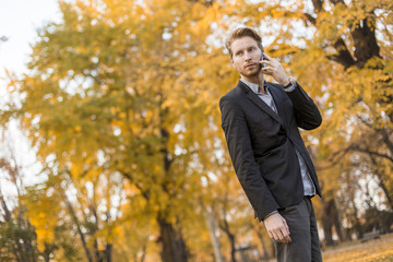 Young man with mobile phone in the autumn park