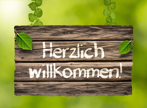 "Herzlich willkommen!" - Holzschild im Grünem