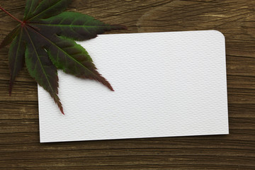 blank business card with leaf on wood desk background