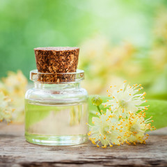 Bottle of essential linden oil and yellow lime flowers.