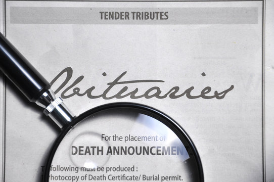 magnifying glass and obituaries advertisement on newspaper