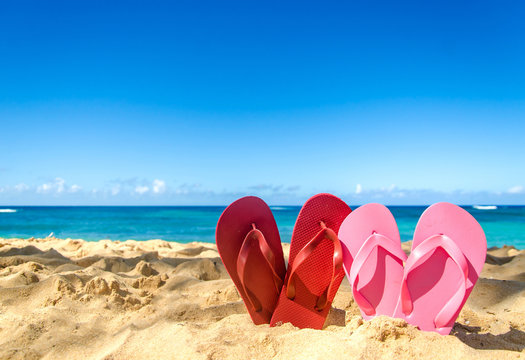 Red and pink flip flops on the sandy beach