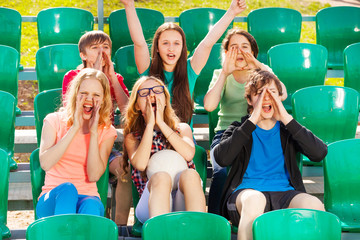 Happy teenagers cheer for the team during game