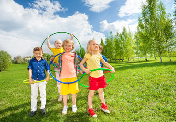 Happy children holding hula hoops during exercises