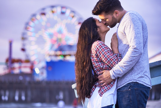 romantic couple kissing in front of santa monica pier