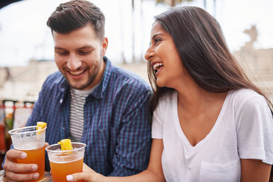 Happy Hispanic Couple Drinking Beer In Outdoor Pub