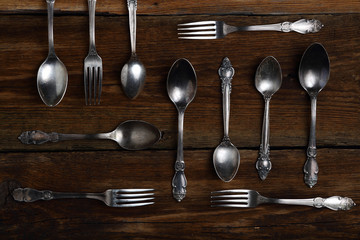 Silver forks and spoons on wooden background.