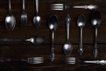 Silver forks and spoons on wooden background.