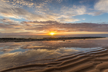 Obraz premium reflection of a beautiful sunrise in a calm tide pool protected by the reef on the Island of Kauai, Hawaii.