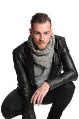 Fototapeta premium Attractive man in a leather jacket and a grey shirt sitting down