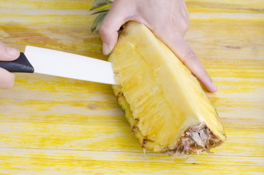 Woman cutting a pineapple over wood.