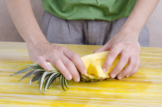 Woman cutting a pineapple over wood.