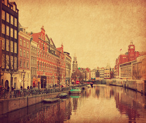 Obraz premium The Singel is one of the numerous canals in Amsterdam, Netherlands . In the background Munttoren . Photo in retro style. Paper texture.