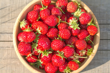 fresh ripe strawberries in a wooden plate, top view